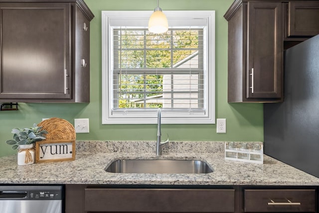 kitchen with light stone countertops, dishwasher, sink, pendant lighting, and dark brown cabinets