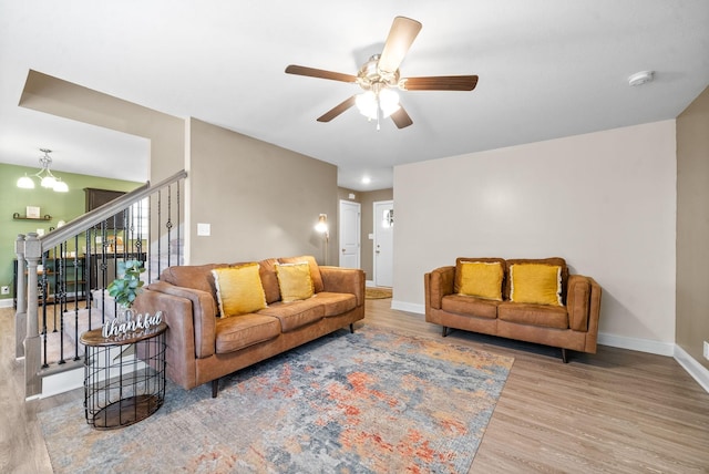 living room featuring ceiling fan with notable chandelier and light hardwood / wood-style floors