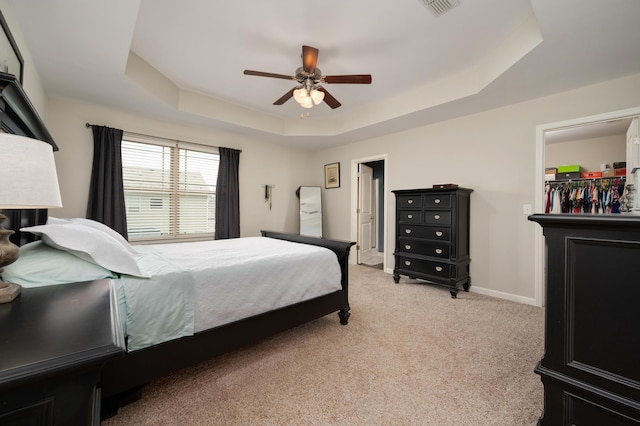 carpeted bedroom with a tray ceiling and ceiling fan