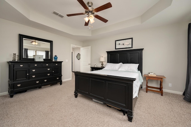 bedroom featuring ceiling fan, light carpet, and a tray ceiling