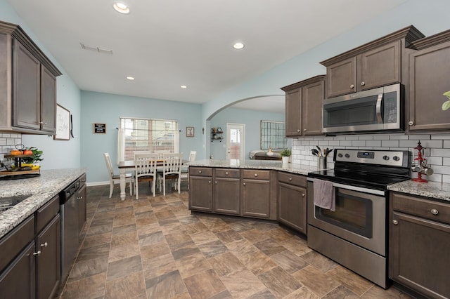 kitchen featuring decorative backsplash, light stone counters, and stainless steel appliances