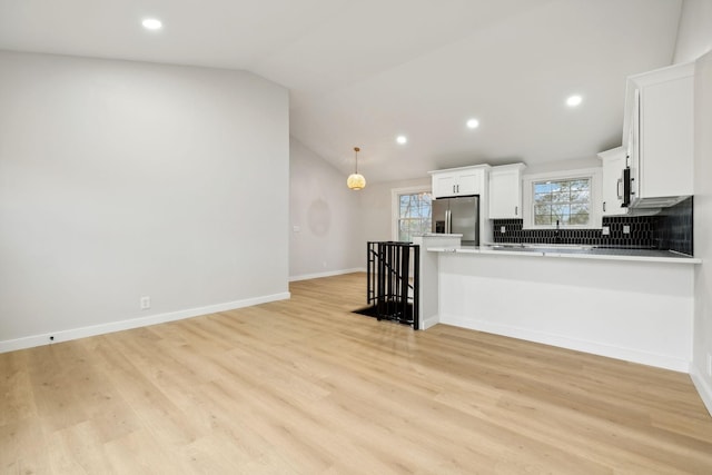 kitchen featuring lofted ceiling, tasteful backsplash, white cabinetry, kitchen peninsula, and stainless steel appliances