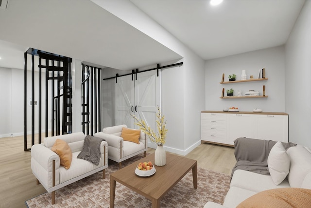 living room with a barn door and light hardwood / wood-style floors