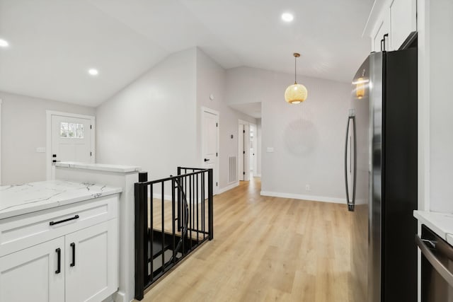 kitchen featuring vaulted ceiling, decorative light fixtures, light stone counters, white cabinetry, and stainless steel appliances