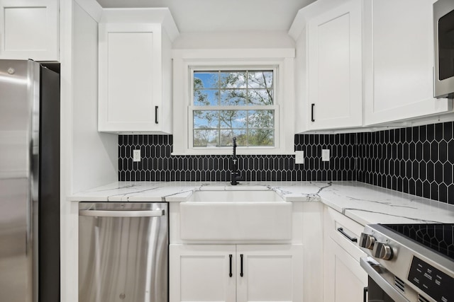 kitchen featuring light stone counters, sink, white cabinets, and appliances with stainless steel finishes