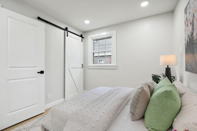 bedroom featuring a barn door and hardwood / wood-style flooring