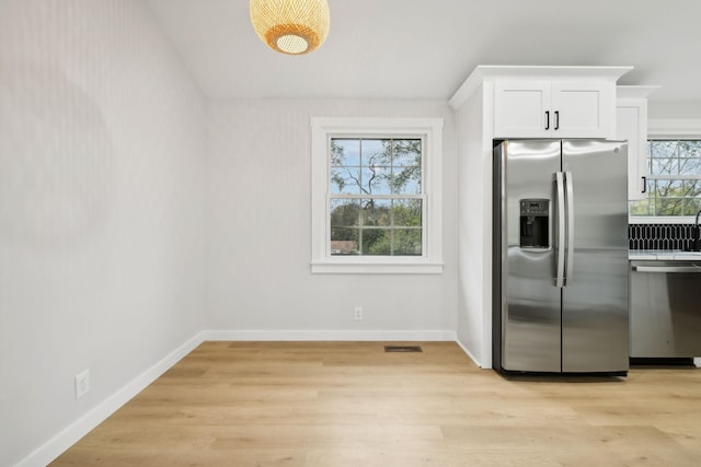 kitchen with white cabinets, stainless steel appliances, light hardwood / wood-style flooring, and plenty of natural light