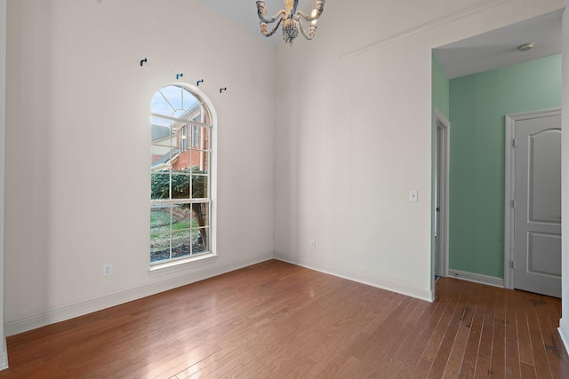 empty room featuring a chandelier and hardwood / wood-style floors