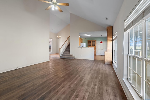 unfurnished living room with ceiling fan with notable chandelier, dark hardwood / wood-style floors, a wealth of natural light, and high vaulted ceiling