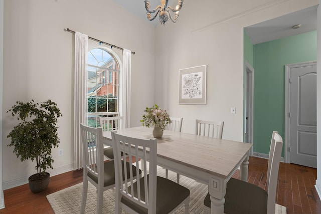 dining area with dark wood-type flooring and a notable chandelier