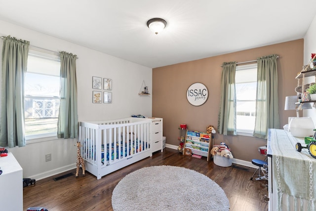 bedroom with dark hardwood / wood-style flooring and a crib