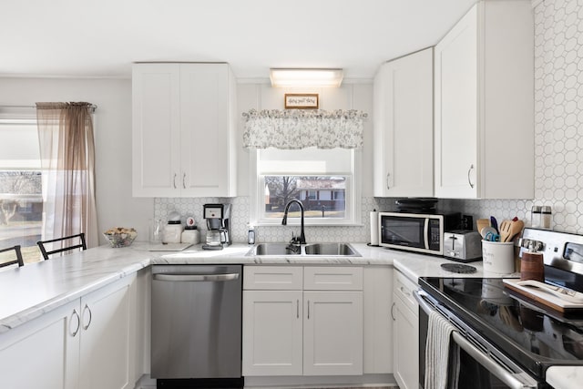 kitchen with a kitchen bar, tasteful backsplash, stainless steel appliances, sink, and white cabinets