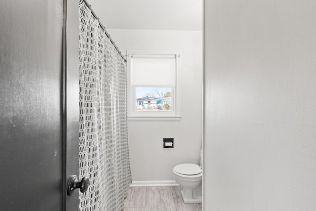 bathroom featuring curtained shower, toilet, and wood-type flooring