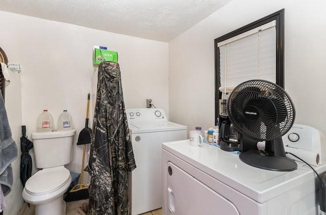 clothes washing area with independent washer and dryer and a textured ceiling