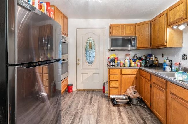 kitchen featuring hardwood / wood-style floors, a textured ceiling, and appliances with stainless steel finishes