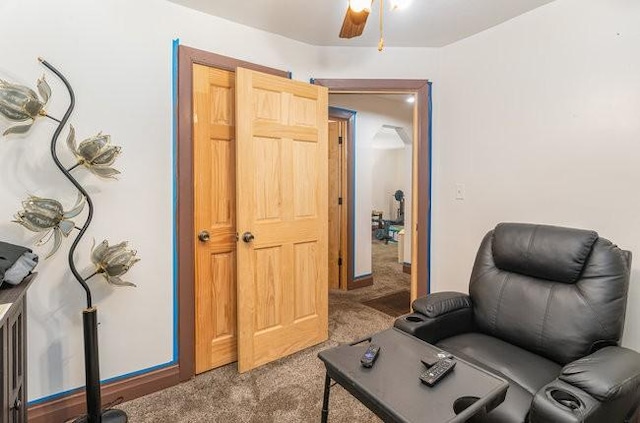 living area with ceiling fan and carpet