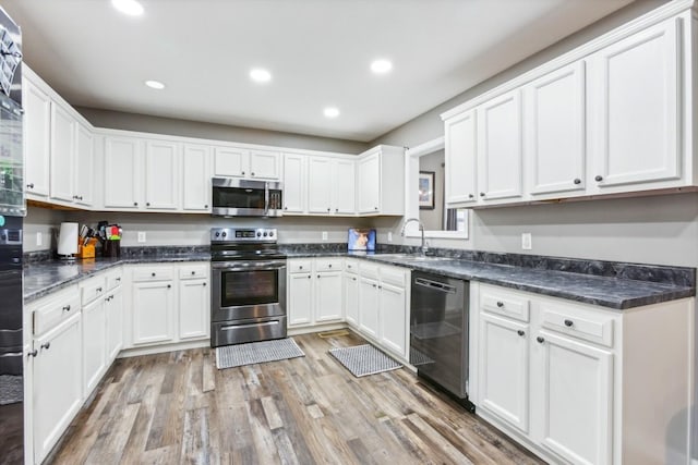 kitchen featuring sink, dark stone countertops, light hardwood / wood-style floors, white cabinetry, and stainless steel appliances