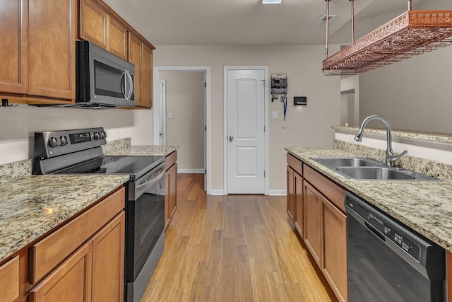 kitchen featuring light stone counters, light wood-type flooring, sink, and appliances with stainless steel finishes