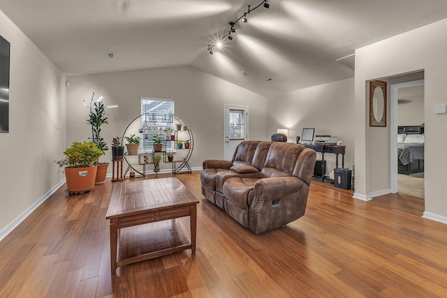 living room with hardwood / wood-style floors, rail lighting, and vaulted ceiling