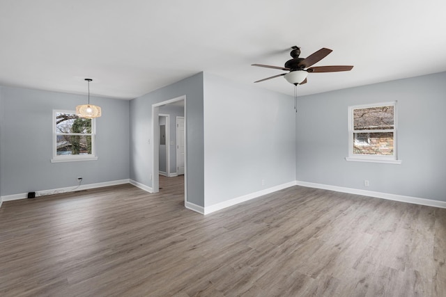 spare room featuring wood finished floors, a ceiling fan, and baseboards