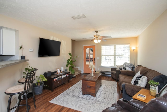 living room featuring ceiling fan, dark hardwood / wood-style flooring, and a textured ceiling