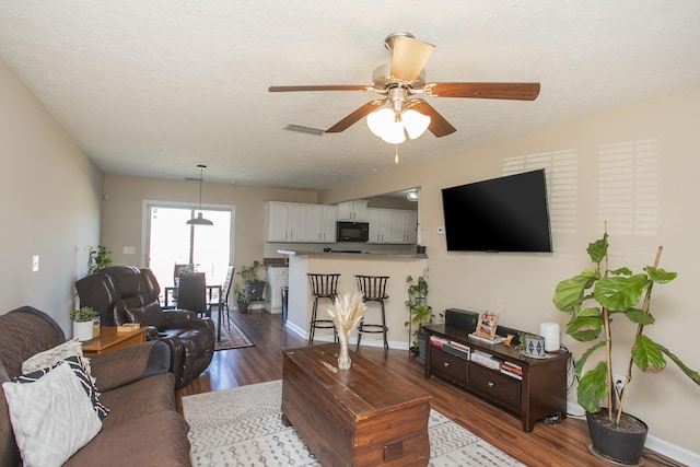 living room with a textured ceiling, hardwood / wood-style flooring, and ceiling fan