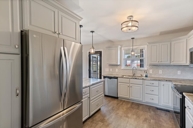 kitchen with sink, stainless steel appliances, pendant lighting, and white cabinetry