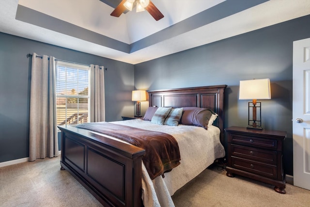 carpeted bedroom featuring ceiling fan and a tray ceiling