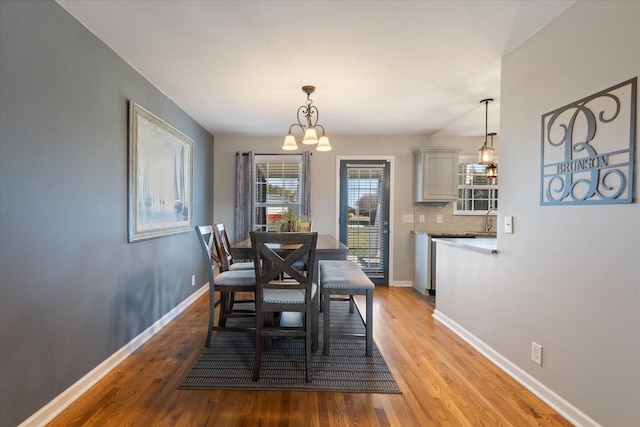 dining space with light hardwood / wood-style flooring, a chandelier, and sink