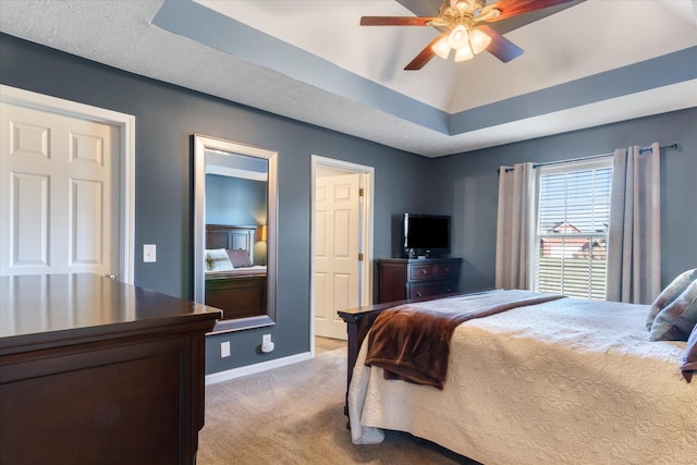 bedroom with ceiling fan, light colored carpet, and a raised ceiling