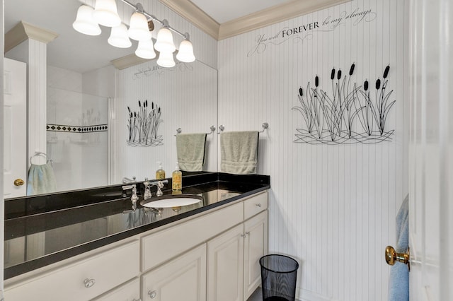 bathroom with a tile shower, vanity, and ornamental molding