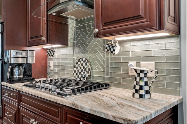 kitchen featuring light stone countertops, tasteful backsplash, stainless steel gas stovetop, and wall chimney range hood