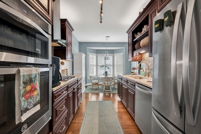 kitchen featuring pendant lighting, sink, light stone countertops, wood-type flooring, and stainless steel appliances