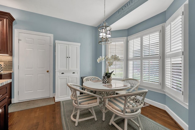 dining area with dark wood-type flooring and a notable chandelier