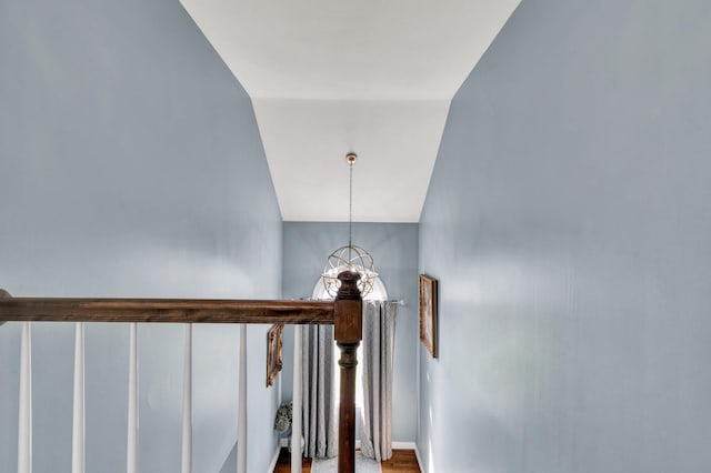 staircase featuring hardwood / wood-style floors, lofted ceiling, and a notable chandelier