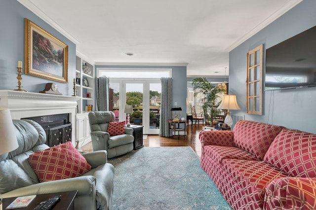 living room with hardwood / wood-style flooring, built in shelves, and crown molding