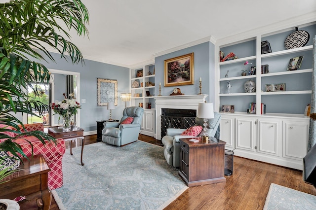 living room with built in shelves, crown molding, and hardwood / wood-style floors