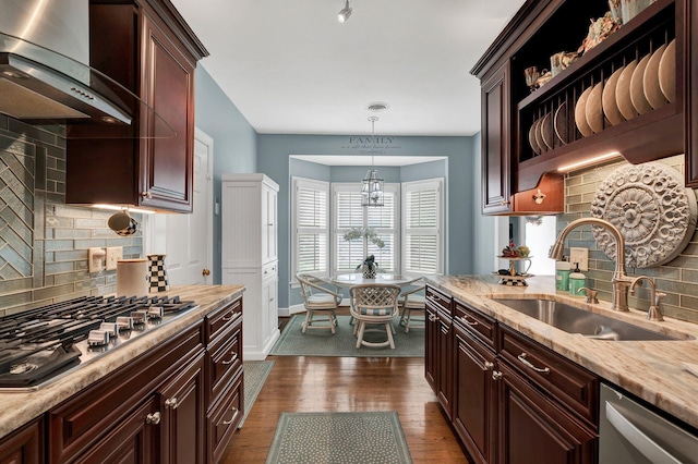 kitchen featuring tasteful backsplash, stainless steel appliances, sink, wall chimney range hood, and decorative light fixtures