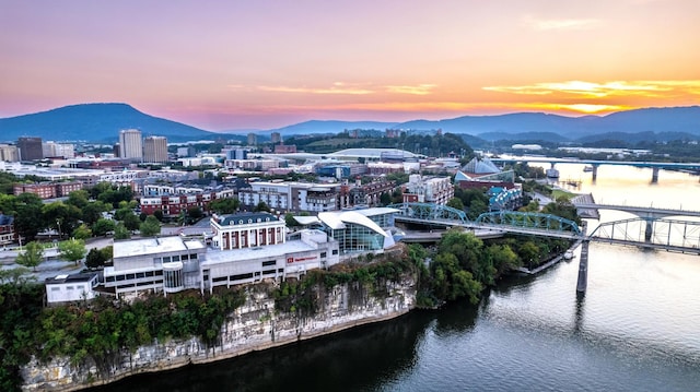 aerial view at dusk featuring a water and mountain view