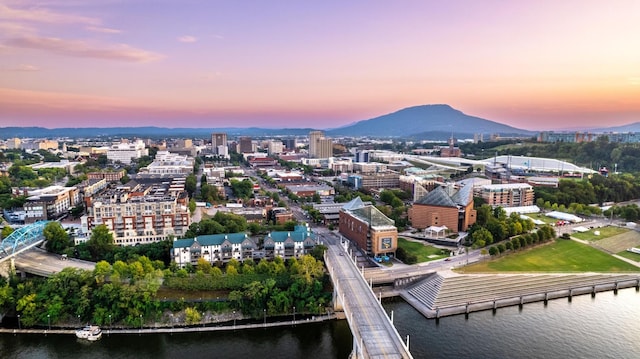 aerial view at dusk featuring a water and mountain view