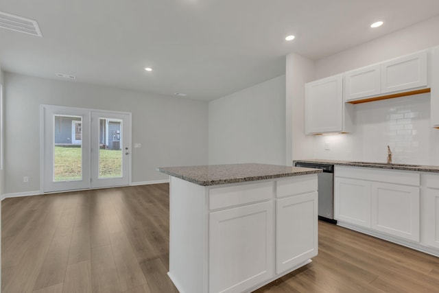 kitchen featuring dishwasher, a center island, and white cabinetry