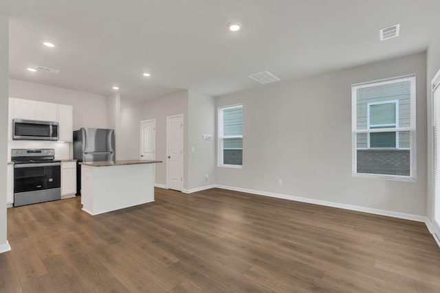 kitchen featuring a center island, white cabinets, dark stone countertops, dark hardwood / wood-style flooring, and stainless steel appliances