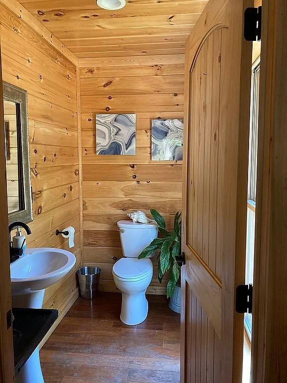 bathroom featuring sink, wooden ceiling, toilet, wooden walls, and hardwood / wood-style flooring