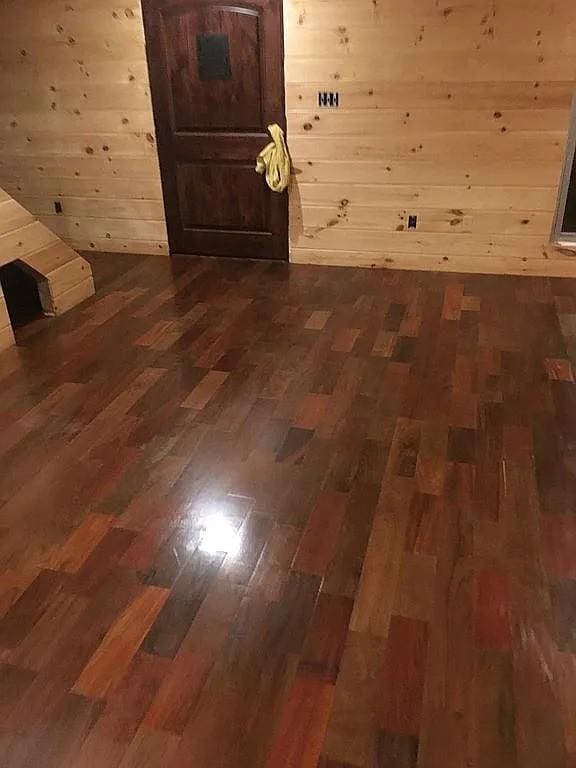 bonus room with dark wood-type flooring and wood walls