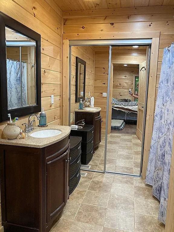 bathroom with vanity, wood ceiling, and wood walls