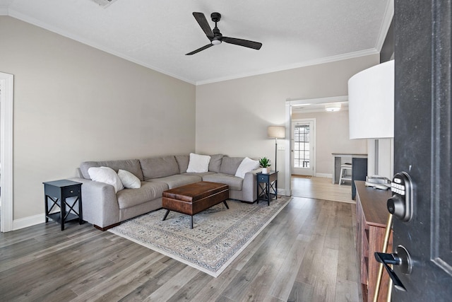 living room with crown molding, ceiling fan, dark wood-type flooring, and a textured ceiling