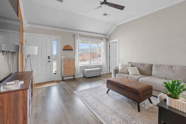 living room featuring lofted ceiling, hardwood / wood-style flooring, ceiling fan, ornamental molding, and a textured ceiling