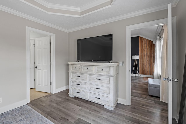 unfurnished bedroom featuring a textured ceiling, light hardwood / wood-style floors, a tray ceiling, and crown molding