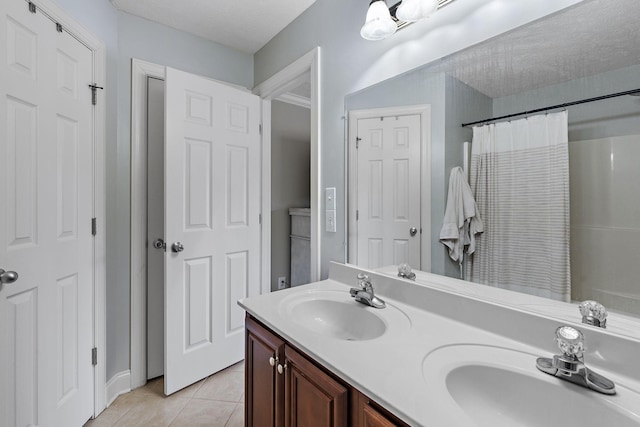 bathroom with tile patterned floors, curtained shower, vanity, and a textured ceiling