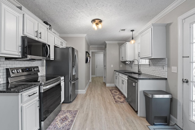 kitchen with sink, tasteful backsplash, decorative light fixtures, white cabinets, and appliances with stainless steel finishes